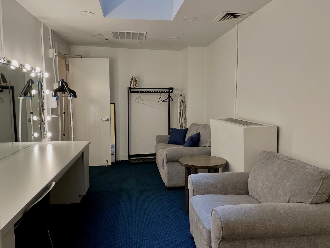 Stage-left dressing room seating, garment racks, and mirror counter